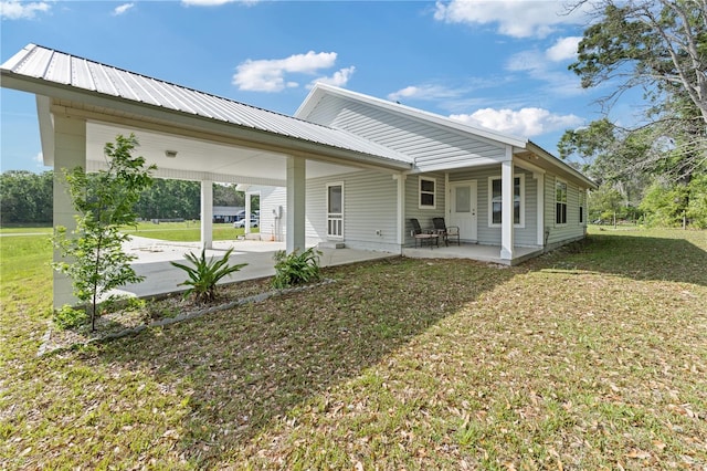 back of property featuring a carport, metal roof, and a lawn