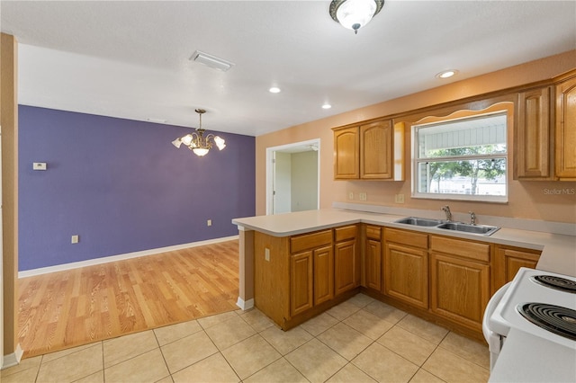 kitchen with a notable chandelier, a peninsula, light countertops, a sink, and white range with electric cooktop
