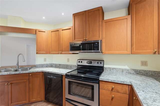 kitchen featuring light stone counters, recessed lighting, brown cabinets, stainless steel appliances, and a sink