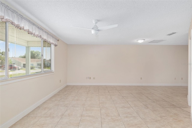 empty room featuring light tile patterned floors, baseboards, a ceiling fan, and a textured ceiling
