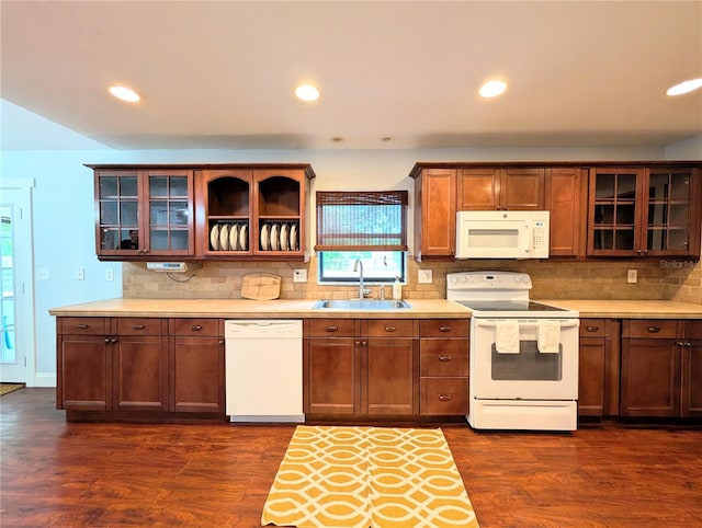 kitchen featuring dark wood-style floors, light countertops, a sink, white appliances, and decorative backsplash