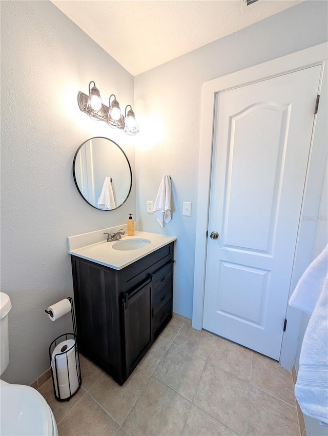 bathroom with toilet, vanity, and tile patterned floors