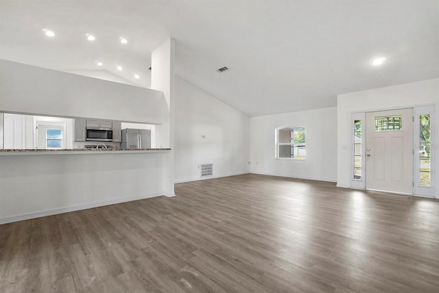 4246 NE 32nd Cir, Ocala, FL 34479 - unfurnished living room with high vaulted ceiling, visible vents, baseboards, and wood finished floors