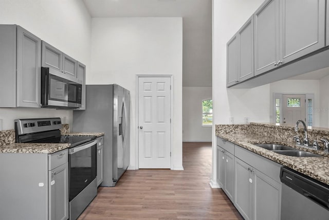 4246 NE 32nd Cir, Ocala, FL 34479 - kitchen with light wood-type flooring, light stone countertops, gray cabinetry, stainless steel appliances, and a sink