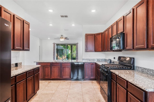 kitchen with light stone counters, a peninsula, a ceiling fan, black appliances, and a sink