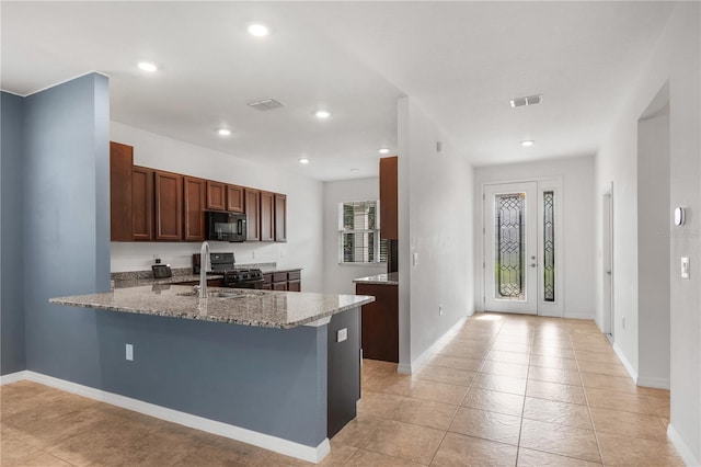 8546 SW 79th Ave, Ocala, FL 34476 - kitchen with black microwave, stainless steel gas range oven, light stone countertops, a peninsula, and light tile patterned floors