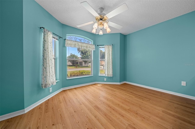 empty room featuring baseboards, wood finished floors, a textured ceiling, and ceiling fan