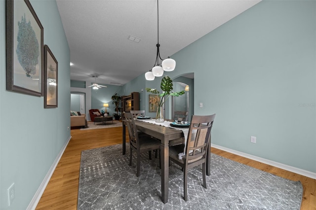 dining space featuring ceiling fan, arched walkways, wood finished floors, and baseboards