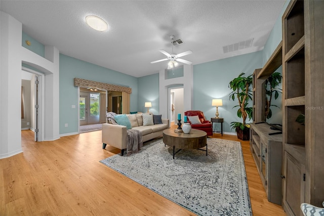living room with arched walkways, light wood-type flooring, and visible vents