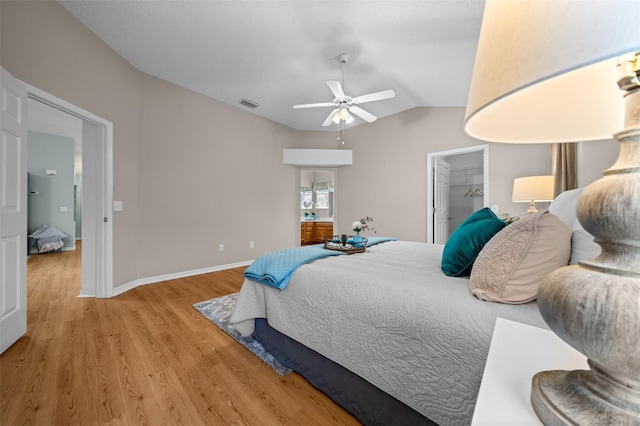 bedroom with lofted ceiling, wood finished floors, visible vents, a ceiling fan, and baseboards