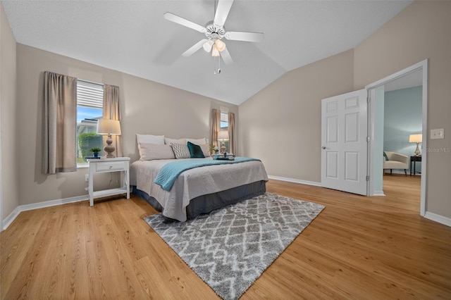 bedroom featuring baseboards, vaulted ceiling, wood finished floors, and multiple windows