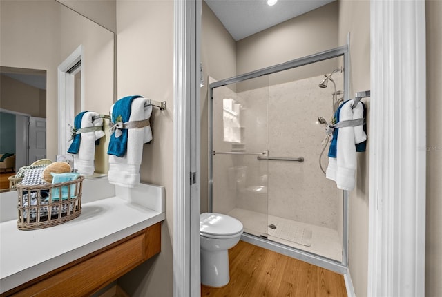 bathroom with vanity, wood finished floors, a shower stall, and toilet