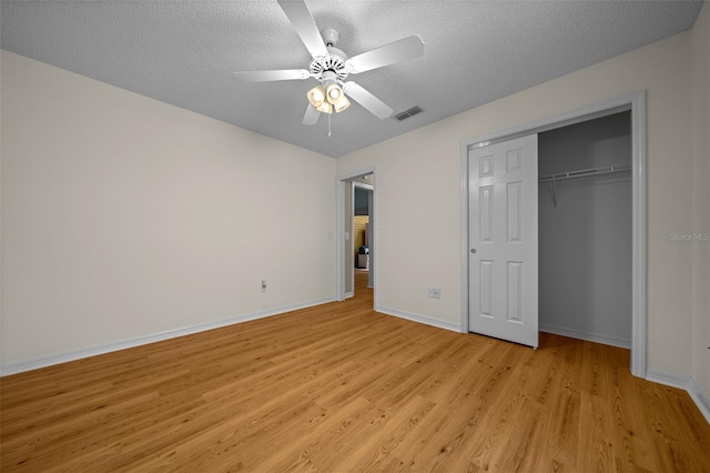 unfurnished bedroom with visible vents, light wood-type flooring, a closet, baseboards, and a textured ceiling