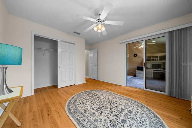 bedroom featuring wood finished floors, a closet, ceiling fan, baseboards, and visible vents