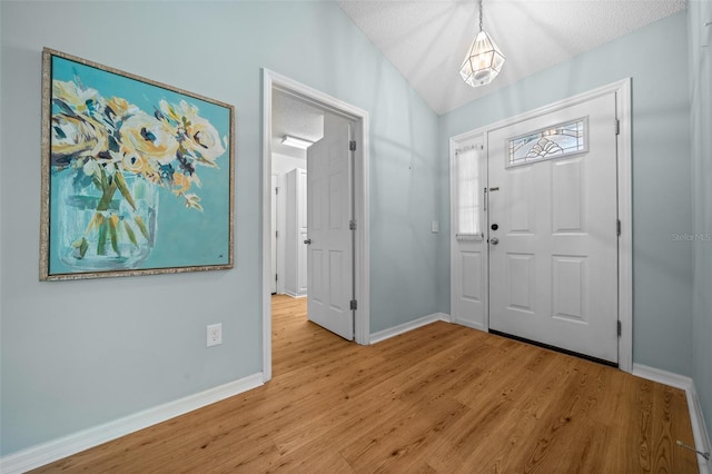 entrance foyer with baseboards, wood finished floors, and a textured ceiling