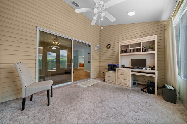 office featuring wooden walls, visible vents, carpet flooring, and a ceiling fan