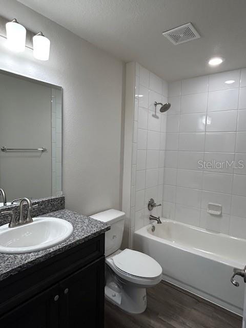 bathroom featuring vanity, visible vents,  shower combination, toilet, and wood finished floors