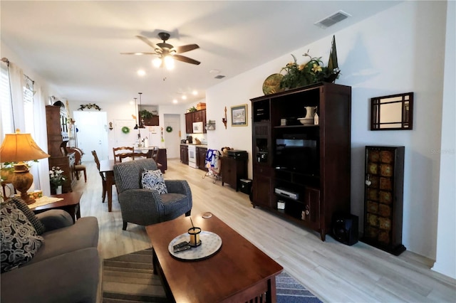 living area featuring visible vents, ceiling fan, and light wood finished floors