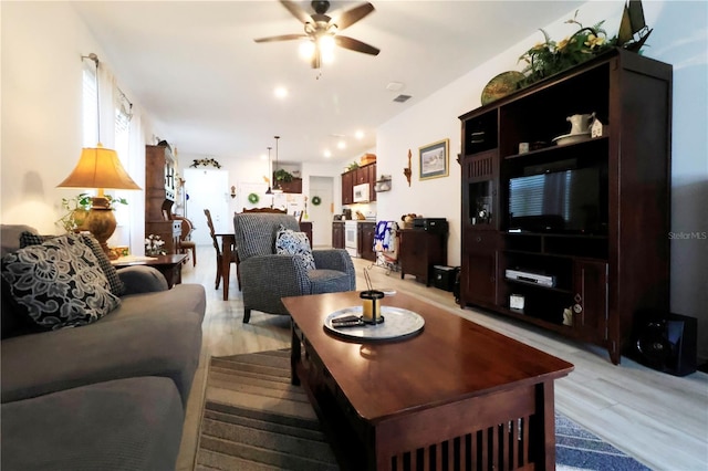 living room with a ceiling fan and light wood finished floors