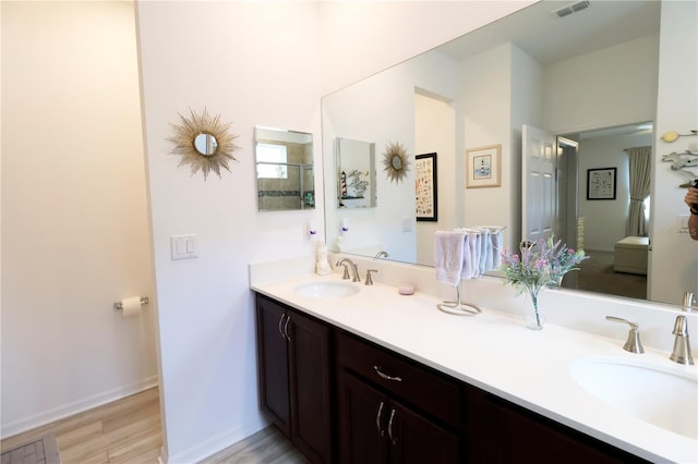full bath with double vanity, wood finished floors, visible vents, and a sink
