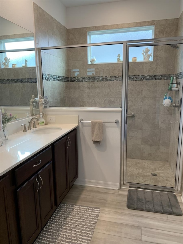 bathroom with a stall shower, wood finished floors, and vanity