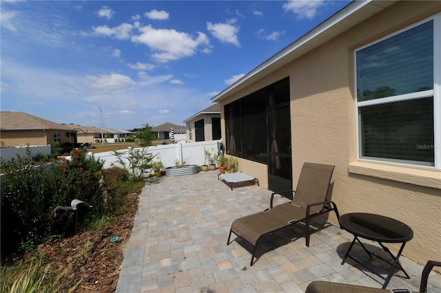view of patio featuring fence, a residential view, and a sunroom