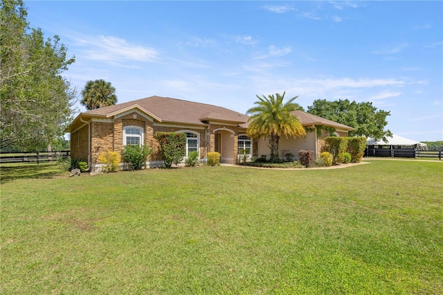 ranch-style home with a front yard, fence, and stone siding