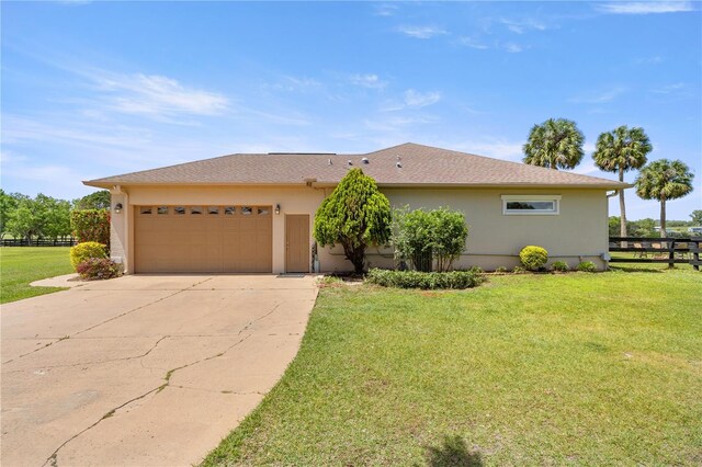ranch-style home featuring stucco siding, driveway, a front yard, a garage, and fence