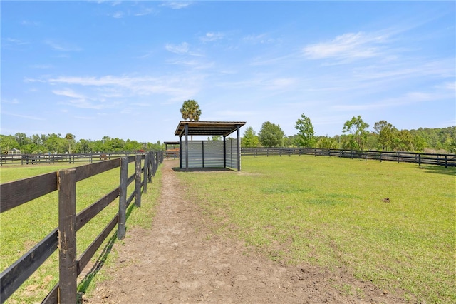 view of yard with a carport, a rural view, an exterior structure, and an outbuilding