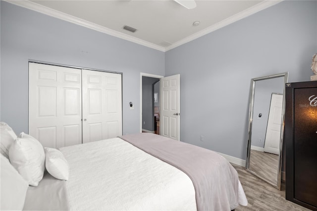bedroom featuring crown molding, wood finished floors, a closet, and visible vents