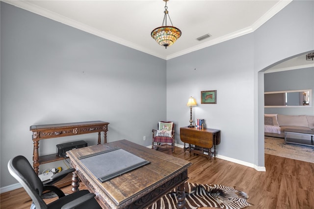 home office featuring visible vents, baseboards, arched walkways, ornamental molding, and wood finished floors