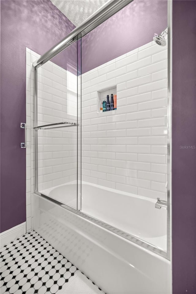 bathroom featuring enclosed tub / shower combo and baseboards