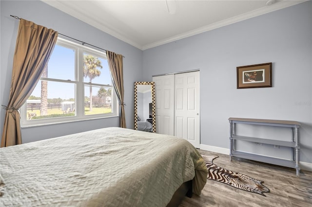 bedroom with crown molding, a closet, a ceiling fan, wood finished floors, and baseboards