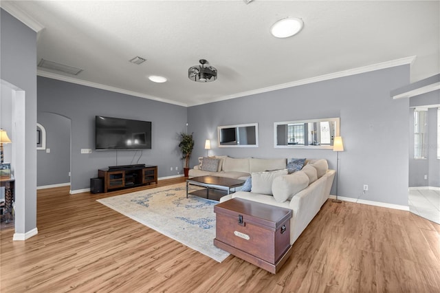 living area featuring arched walkways, light wood finished floors, baseboards, and ornamental molding