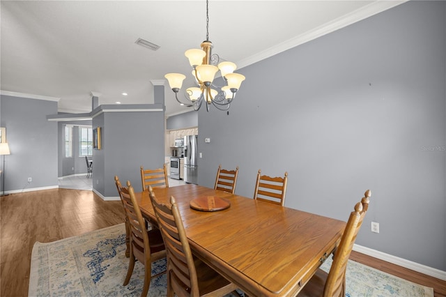 dining area featuring crown molding, visible vents, wood finished floors, baseboards, and a notable chandelier