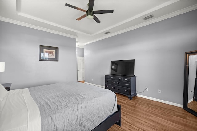 bedroom with crown molding, visible vents, and wood finished floors