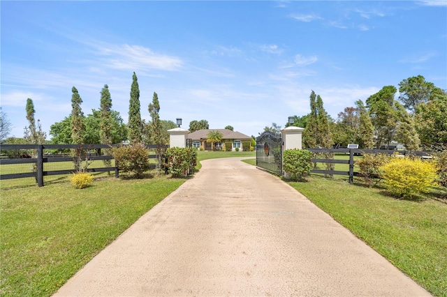exterior space featuring driveway, fence, and a lawn
