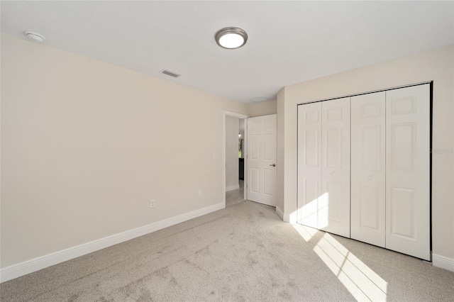 unfurnished bedroom featuring a closet, visible vents, light colored carpet, and baseboards