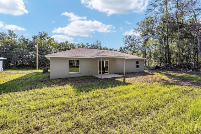 rear view of house featuring a yard, a patio area, central AC unit, and stucco siding