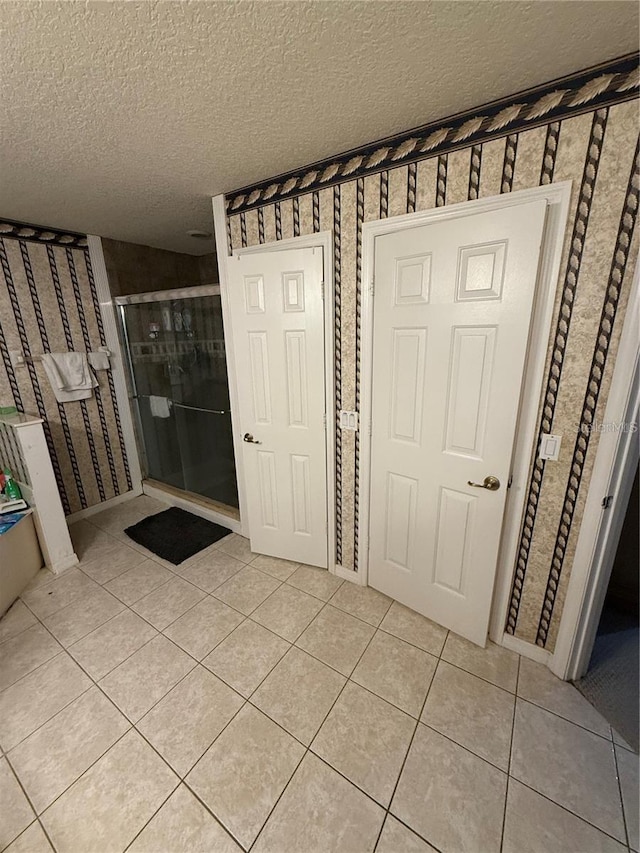 interior space with a stall shower, tile patterned flooring, and a textured ceiling