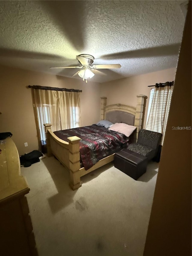 bedroom featuring carpet floors, a ceiling fan, and a textured ceiling