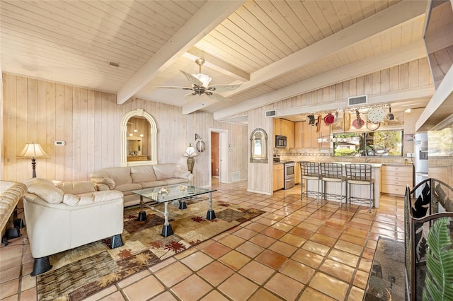 31 SE Chinica Dr, Summerfield, FL 34491 - living room with wooden walls, ceiling fan, light tile patterned floors, and a wood ceiling with exposed beams