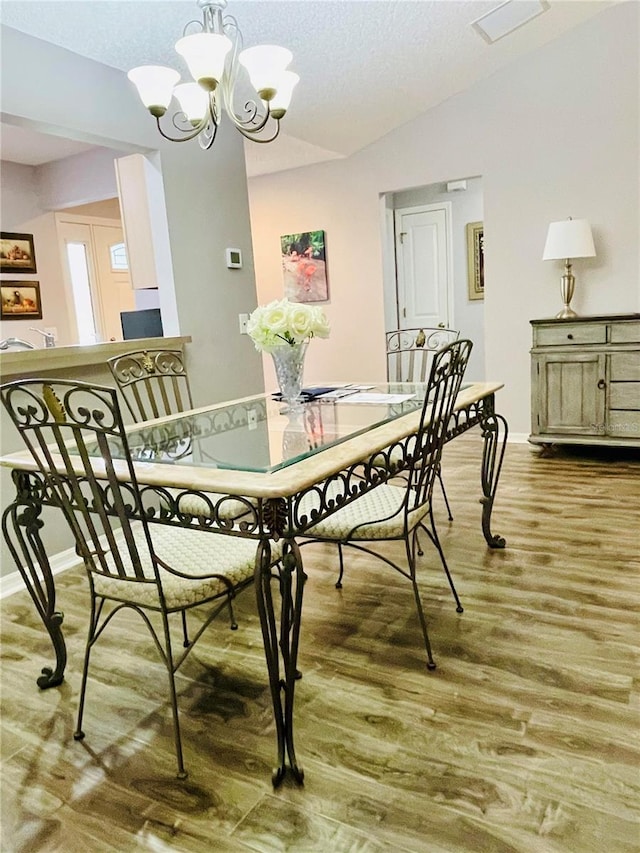 dining room featuring baseboards, an inviting chandelier, wood finished floors, and vaulted ceiling