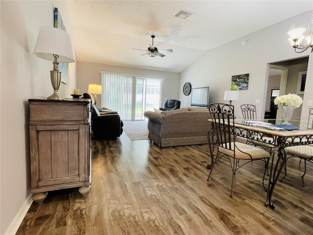 living room featuring visible vents, ceiling fan with notable chandelier, wood finished floors, and vaulted ceiling