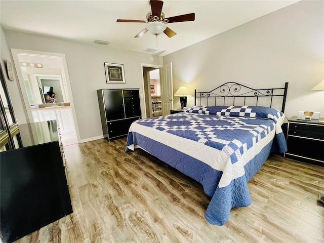 bedroom with a ceiling fan, baseboards, visible vents, and wood finished floors