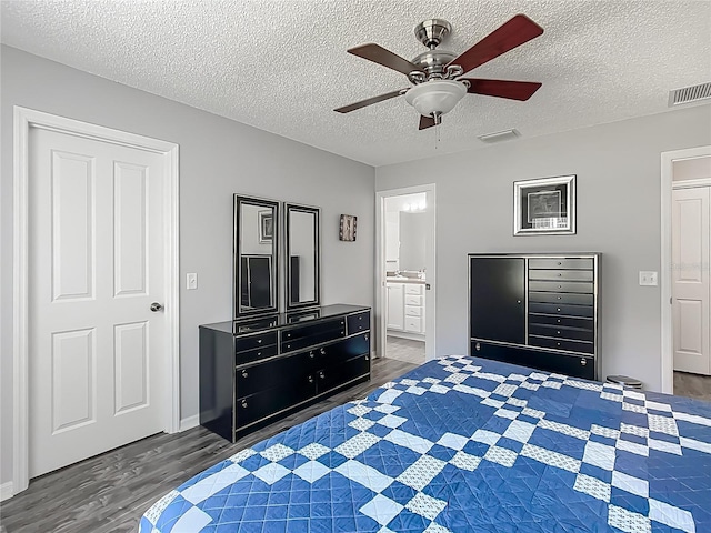 bedroom with visible vents, a textured ceiling, and wood finished floors