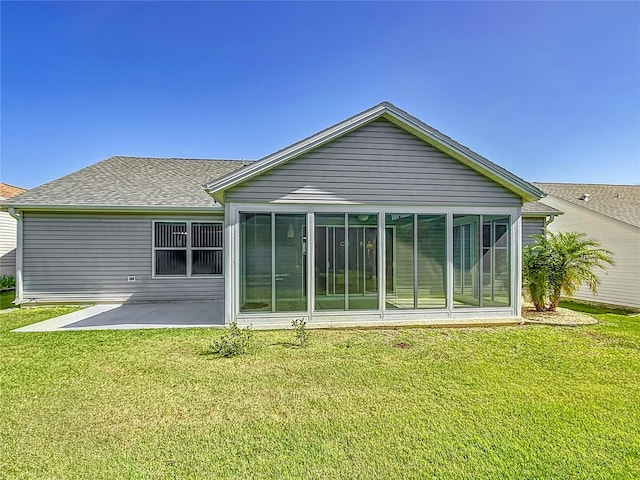 rear view of house featuring roof with shingles, a yard, a sunroom, and a patio area
