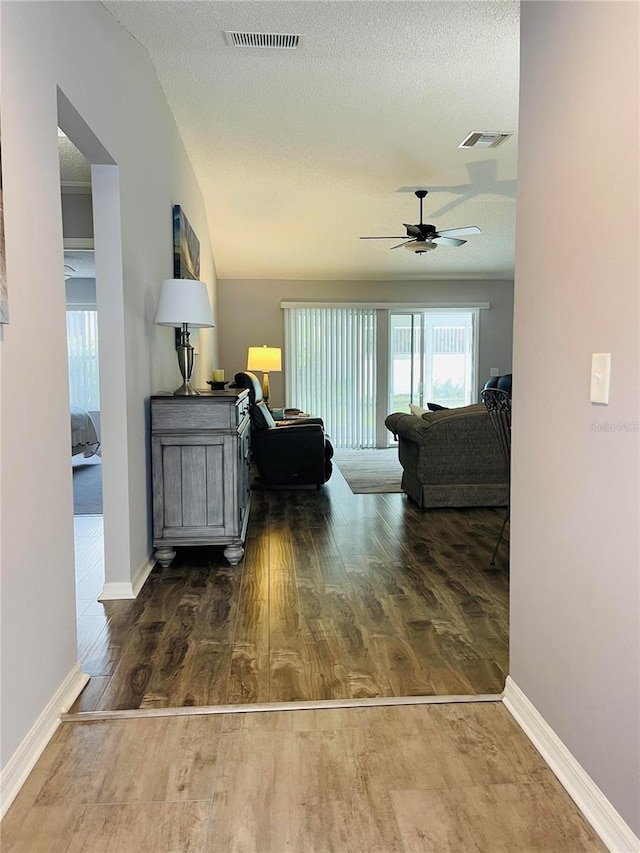 living room with a ceiling fan, wood finished floors, and visible vents