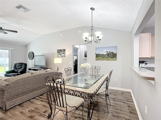 dining space with a textured ceiling, visible vents, wood finished floors, baseboards, and lofted ceiling