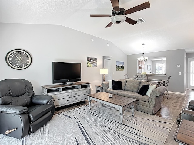 living area with visible vents, ceiling fan with notable chandelier, wood finished floors, and lofted ceiling